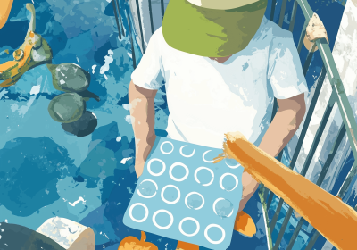 Young boy in construction vehicle t-shirt and cap sitting outdoors holding blue water play tray with circular holes